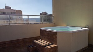 A hot tub on a balcony with a view of buildings in the background.