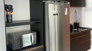 Una cocina compacta con un refrigerador de acero inoxidable, un microondas y un lavamanos.