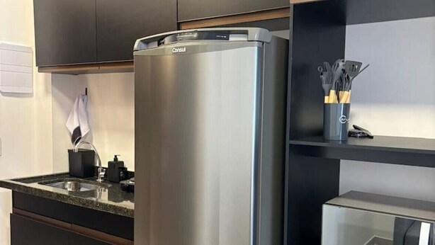 A modern kitchen with dark cabinetry, a stainless steel refrigerator, and a built-in microwave.