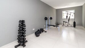A modern gym with a bench press, dumbbells, and a squat rack.