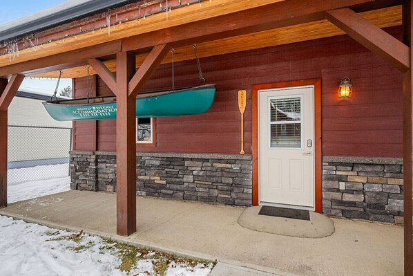 A wooden building with a stone foundation, a white door, and a covered porch area.