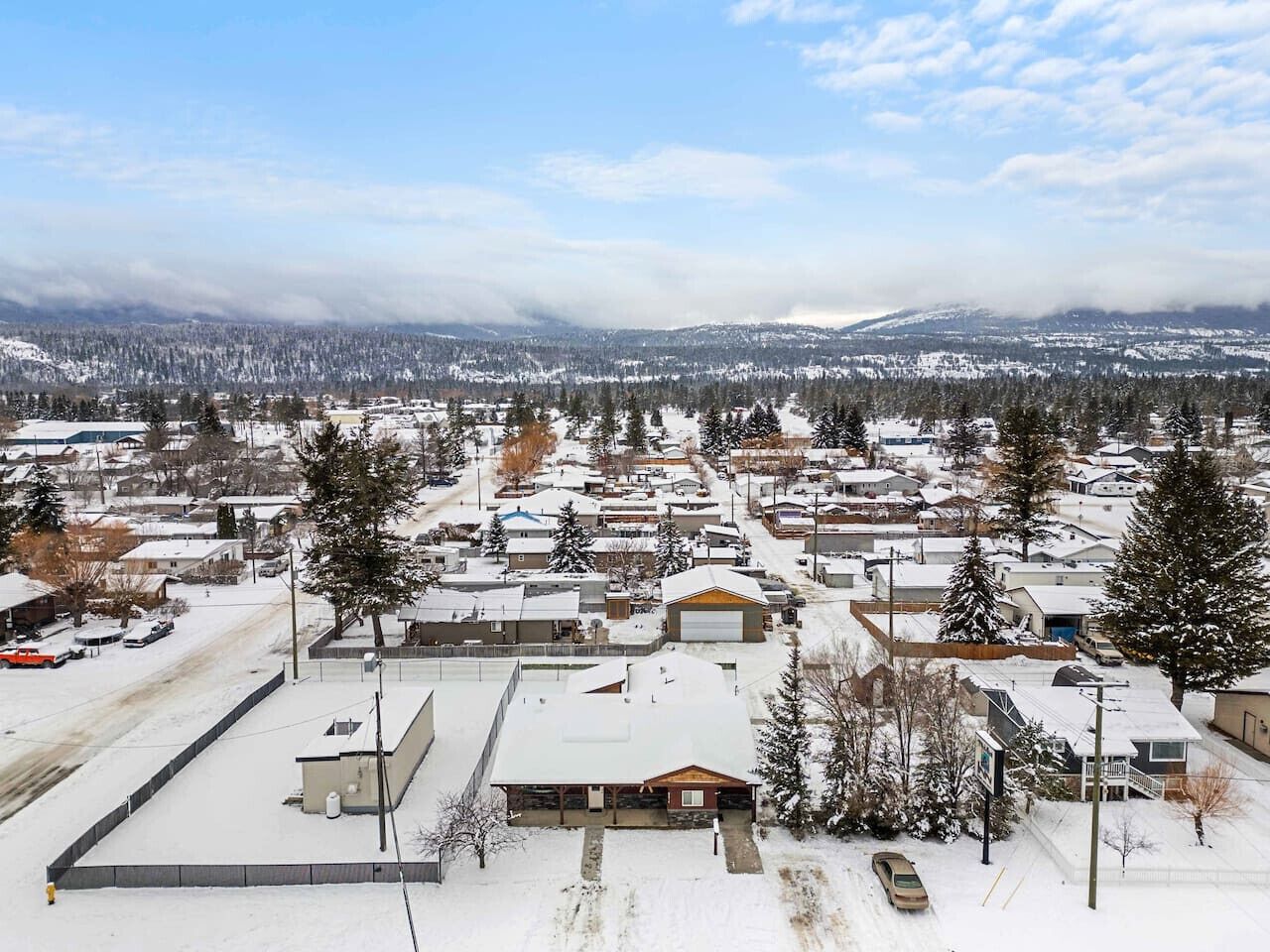 Zona residencial cubierta de nieve con casas, árboles y cielo despejado.