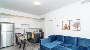 A modern apartment with a kitchenette, a dining area, and a living room with a blue sofa.