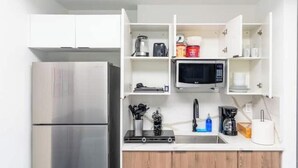 Una cocina compacta con un refrigerador de acero inoxidable, un microondas y una cafetera.
