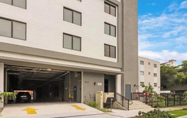 Un bâtiment moderne avec une entrée de garage, un escalier et un ciel dégagé.