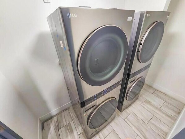 Deux machines à laver LG, fixées au mur, dans une pièce dont le sol est recouvert de carrelage.