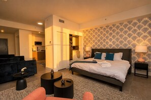 Habitación de hotel moderna con una cama grande, un sofá, una mesita y una pared con estampado.