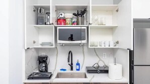 A compact kitchen with a built-in microwave, a coffee maker, and a sink.