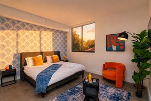 Une chambre moderne avec un grand lit, une table de chevet, une chaise, une fenêtre donnant sur un beau paysage et une plante.