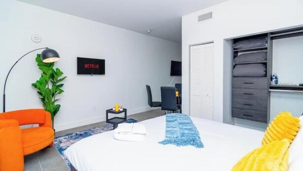Une chambre d’hôtel moderne équipée d’un lit, d’un bureau, d’une chaise, d’une télévision et d’une armoire.