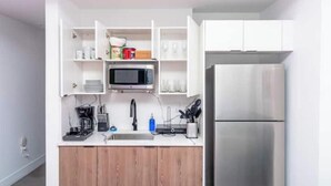 Una cucina moderna con mobili bianchi, un frigorifero in acciaio inossidabile, un forno a microonde e un lavello con rubinetto.