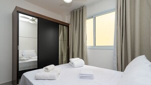 Ein Hotelzimmer mit Bett, Kleiderschrank, Fenster mit Vorhängen und Deckenventilator.