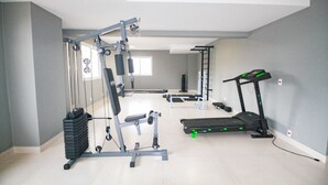 Ein Heimfitnessraum mit einer Hantelbank, einem Squat-Gestell, einem Laufband und einer Klimmzugstange.