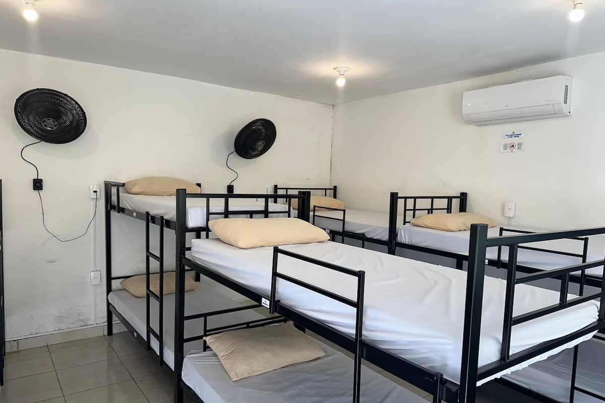 Ein Schlafraum mit Etagenbetten, Deckenventilator, Klimaanlage und Steckdose.