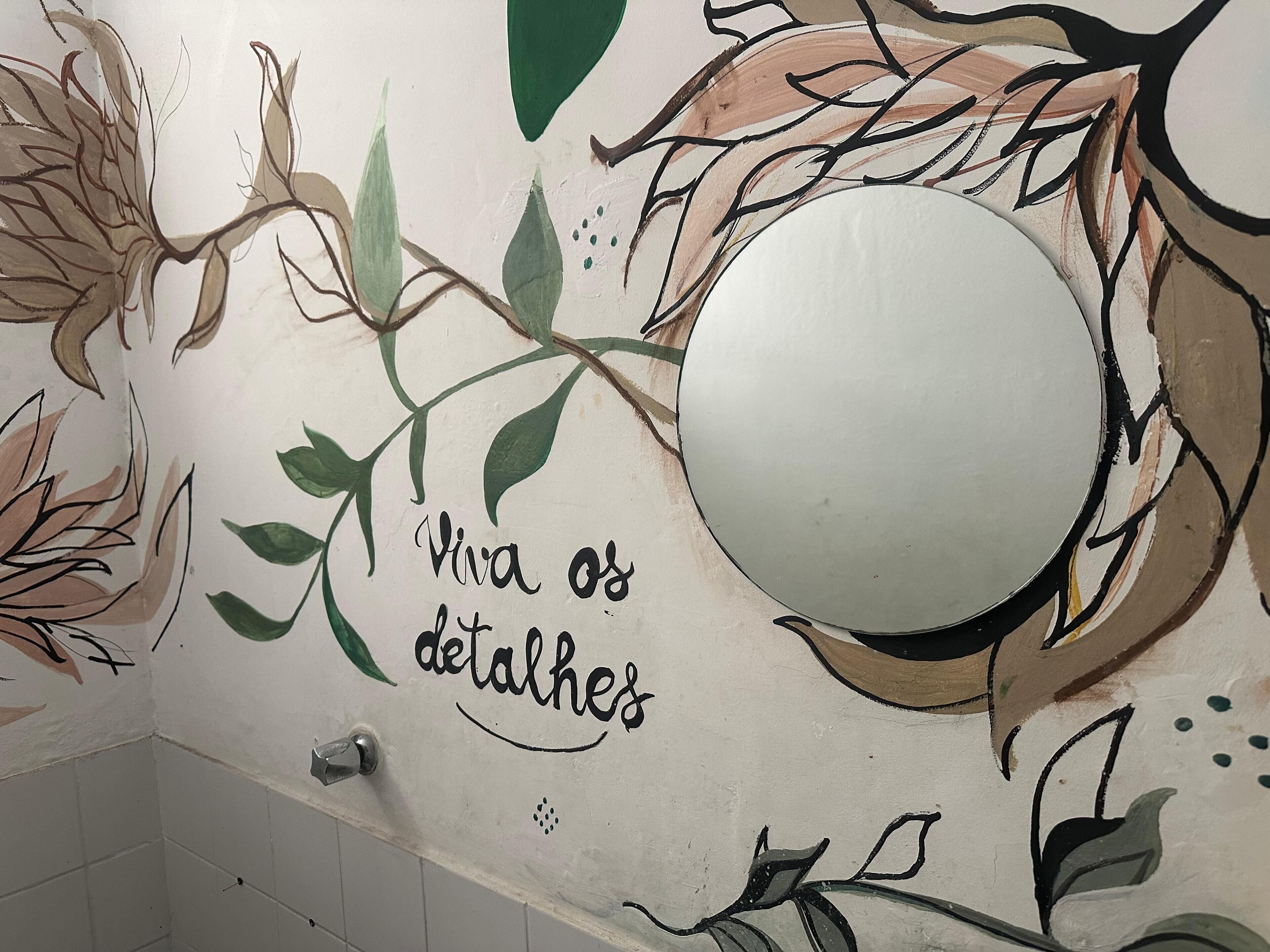 A wall with a circular mirror and floral artwork.