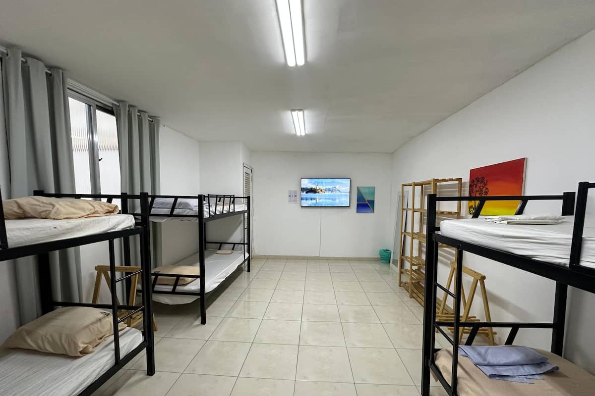 Ein Schlafsaalzimmer mit Etagenbetten, einem Fernseher und Bildern an den Wänden.