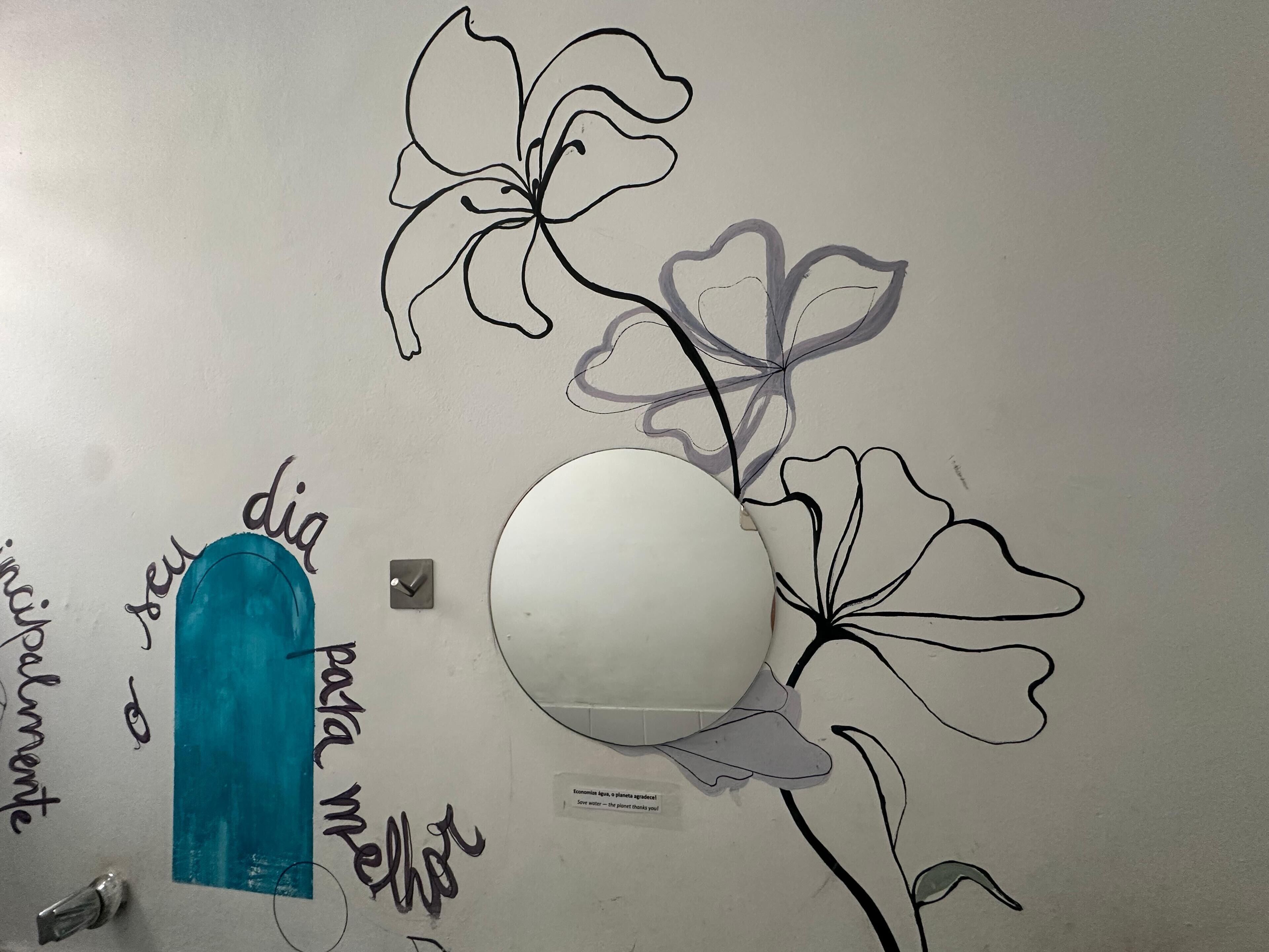 Un mur avec un grand miroir blanc, une porte bleue et des motifs floraux décorant le mur.