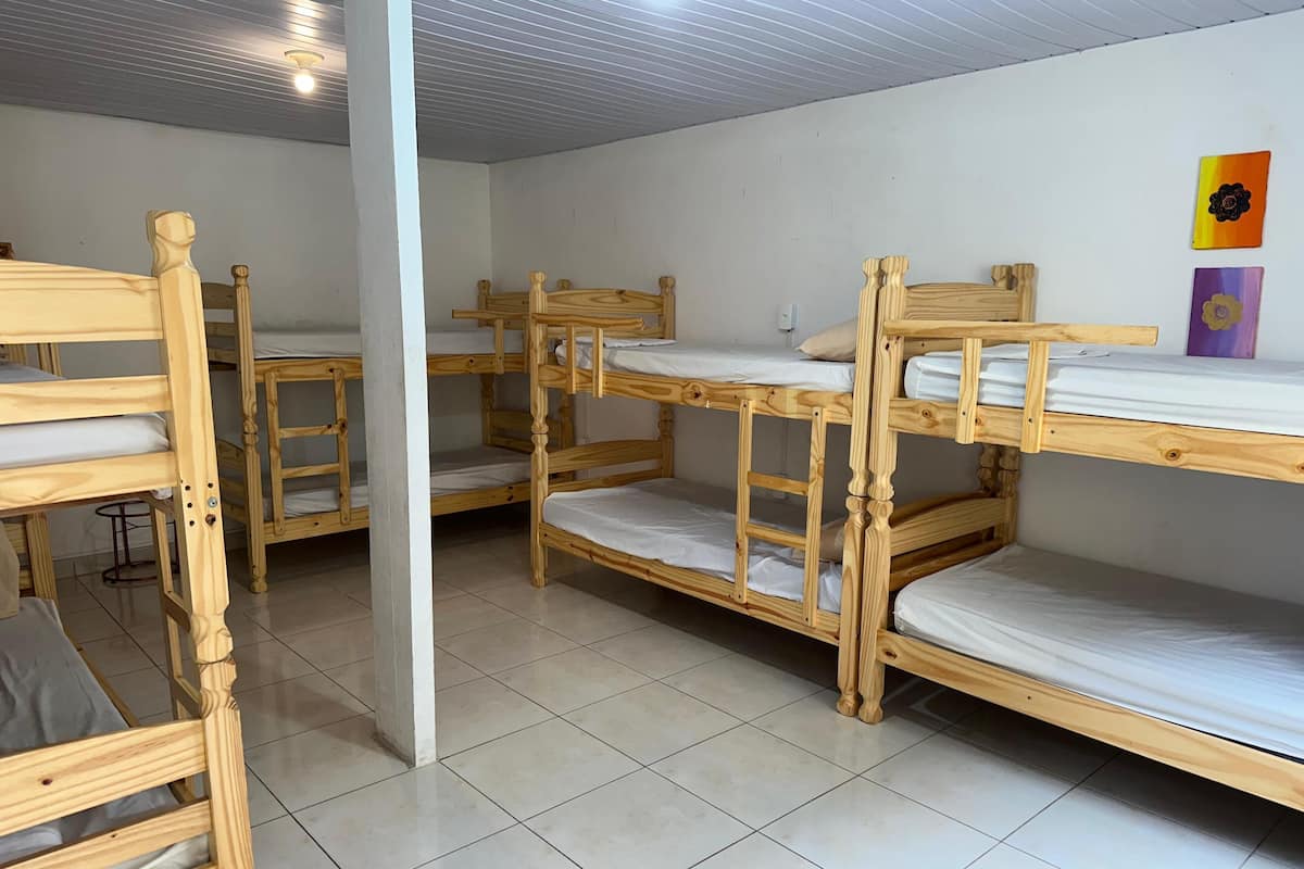 Ein Schlafsaalzimmer mit Etagenbetten, Fliesenboden und weißer Wand mit zwei Blumendekorationen.