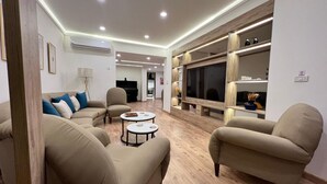 A modern living room with beige sofas, a round coffee table, and a TV mounted on a wooden wall.