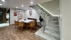 A modern kitchen with a dining area, wooden flooring, and a staircase with marble steps.