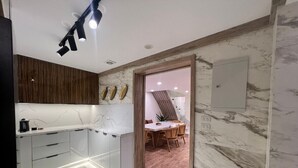 A modern kitchen with white cabinets, a wooden countertop, and a dining area with a wooden table and chairs.