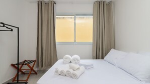 A hotel room with a bed, a window with curtains, a floor lamp, and a drying rack. - Studio 413 - sem cozinha (São Paulo)