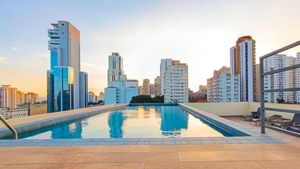 A rooftop pool with a cityscape view, surrounded by high-rise buildings. - Studio 617 - Santana (São Paulo)