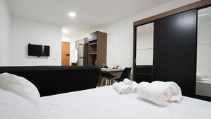 A hotel room with a bed, a desk, a chair, a TV, and a wardrobe. - Studio 617 - Santana (São Paulo)