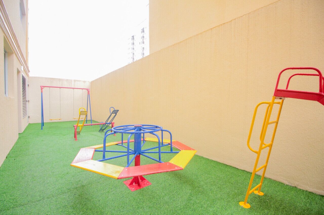 A children's play area with various equipment including a seesaw, a swing set, and a climbing structure.