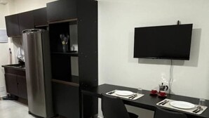 Una cocina moderna con refrigerador empotrado y un comedor con dos sillas negras y una mesa.