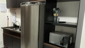 Una cocina con refrigerador de acero inoxidable, microondas y pileta.