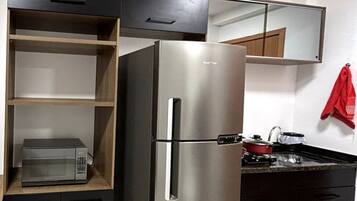 Een koelkast, een magnetron, een kookplaat, kookgerei, borden en bestek