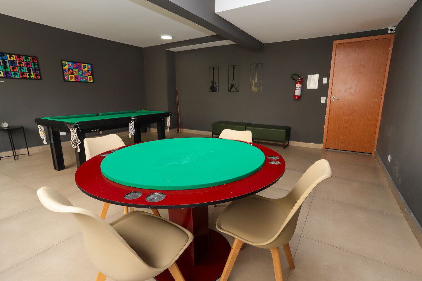 A room with a pool table, chairs, and a door.