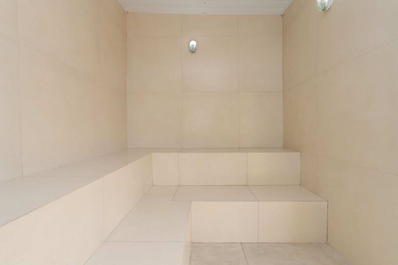 Et badeværelse med beige fliser, et bruseområde og et toilet.