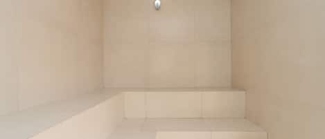 A bathroom with beige tiles, a shower area, and a toilet.