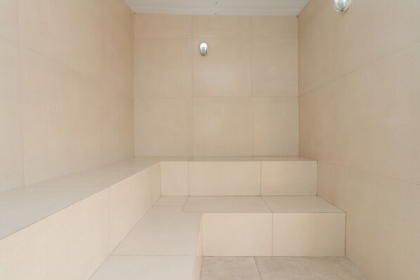 A bathroom with beige tiles, a shower area, and a toilet.