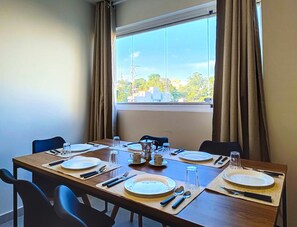Mesa de comedor para cuatro personas, con vista a la ciudad a través de un gran ventanal.