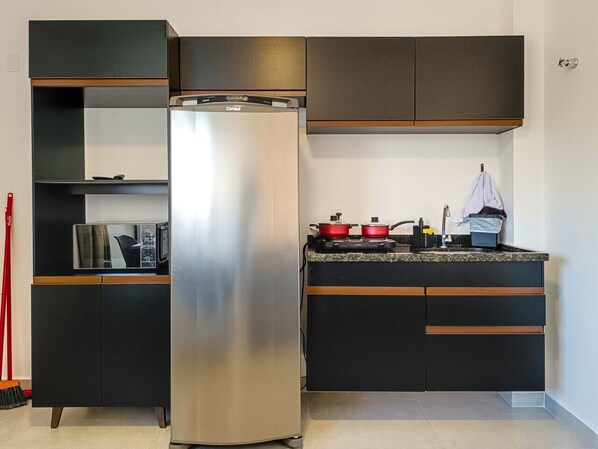 Una cocina compacta con refrigerador de acero inoxidable, microondas y estufa.