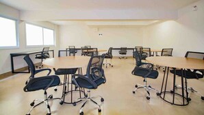 Un salón de conferencias con una gran mesa ovalada y varias sillas de oficina negras.