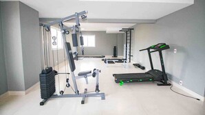 A home gym with a pull-up bar, weight bench, and treadmill.