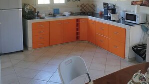 A kitchen with white cabinets, a microwave, and a refrigerator. - BEAUTIFUL 1ST-FLOOR VILLA APARTMENT (Sainte-Anne)