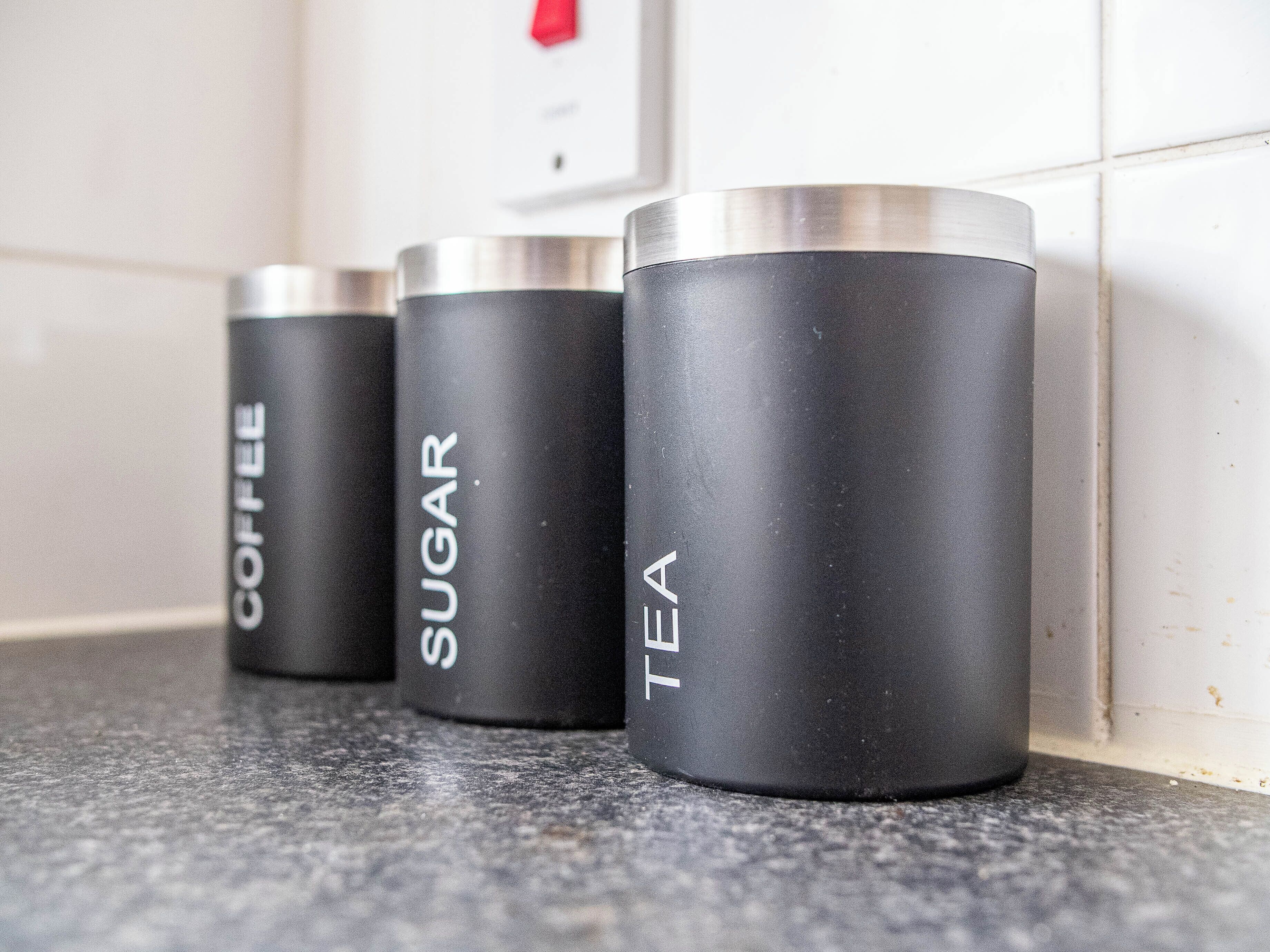 Tres recipientes negros con etiquetas sobre una encimera de cocina.