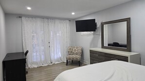 Hotelkamer met een bed, bureau, stoel, een aan de muur bevestigde televisie en een grote spiegel.