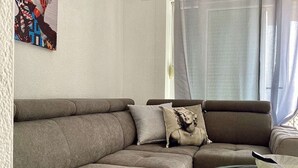 Una sala de estar con un sofá modular, una mesa de centro de vidrio y un cuadro en la pared.