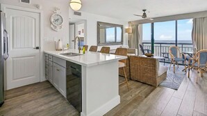 Une cuisine moderne avec un îlot central, un coin repas doté de meubles en osier et un balcon offrant une vue dégagée.