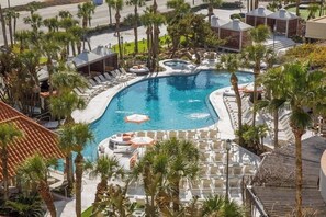 A resort pool with sun loungers and palm trees.
