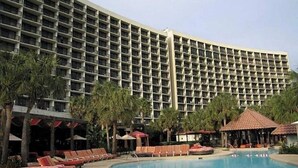 Un hôtel doté d’une grande piscine, de chaises longues et de palmiers.