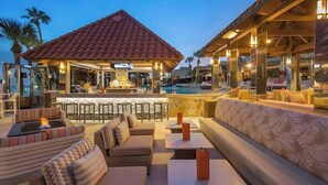 Un espace de détente extérieur comprenant des sièges, une piscine et un bar.