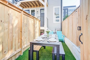 A wooden fence, a table set for dining, and a blue chair in a backyard.