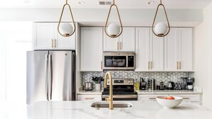 A modern kitchen with white cabinets, stainless steel appliances, and a marble countertop.
